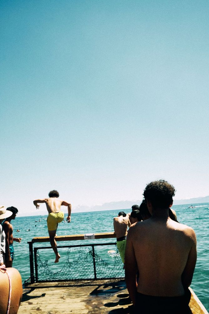 Friends jumping off a pier into a lake